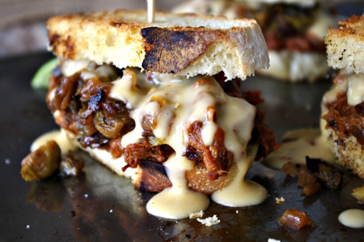 Chipotle Lime Brisket Sandwich topped with Sauteed Brussels Sprouts, Onions and Peppers AND Modelo Cheese Sauce